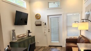 A modern kitchen with a dining area, wooden flooring, a ceiling fan, and a TV mounted on the wall. - Ranch Cabin
Modern Tiny home on beautiful Ranch! (Tyler)