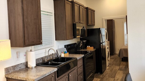 A modern kitchen with dark wooden cabinets, granite countertops, and stainless steel appliances. - Ranch Cabin
Modern Tiny home on beautiful Ranch! (Tyler)