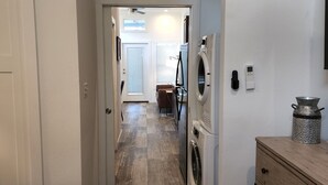 A laundry room with a washing machine and dryer, a wooden cabinet, and a door leading to another room. - Ranch Cabin
Modern Tiny home on beautiful Ranch! (Tyler)