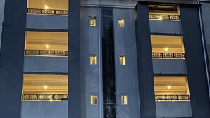 A multi-story building with balconies, air conditioning units, and a central vertical feature. - Moz One Executive Guest Rooms-Tourggourt (Abuja)