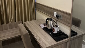 A compact room with a wooden desk, a kettle, a mug, and a power outlet. - Moz One Executive Guest Rooms-Tourggourt (Abuja)