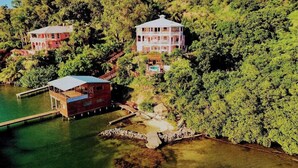 A resort with multiple buildings, a dock, and a pool area surrounded by dense greenery. - El Palacio Rosa - The Bay Suite (Jose Santos Guardiola)