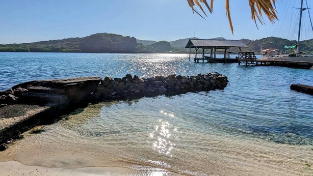 A clear lake with a rocky shoreline, a wooden pier, and a small shelter. - El Palacio Rosa - The Bay Suite (Jose Santos Guardiola)