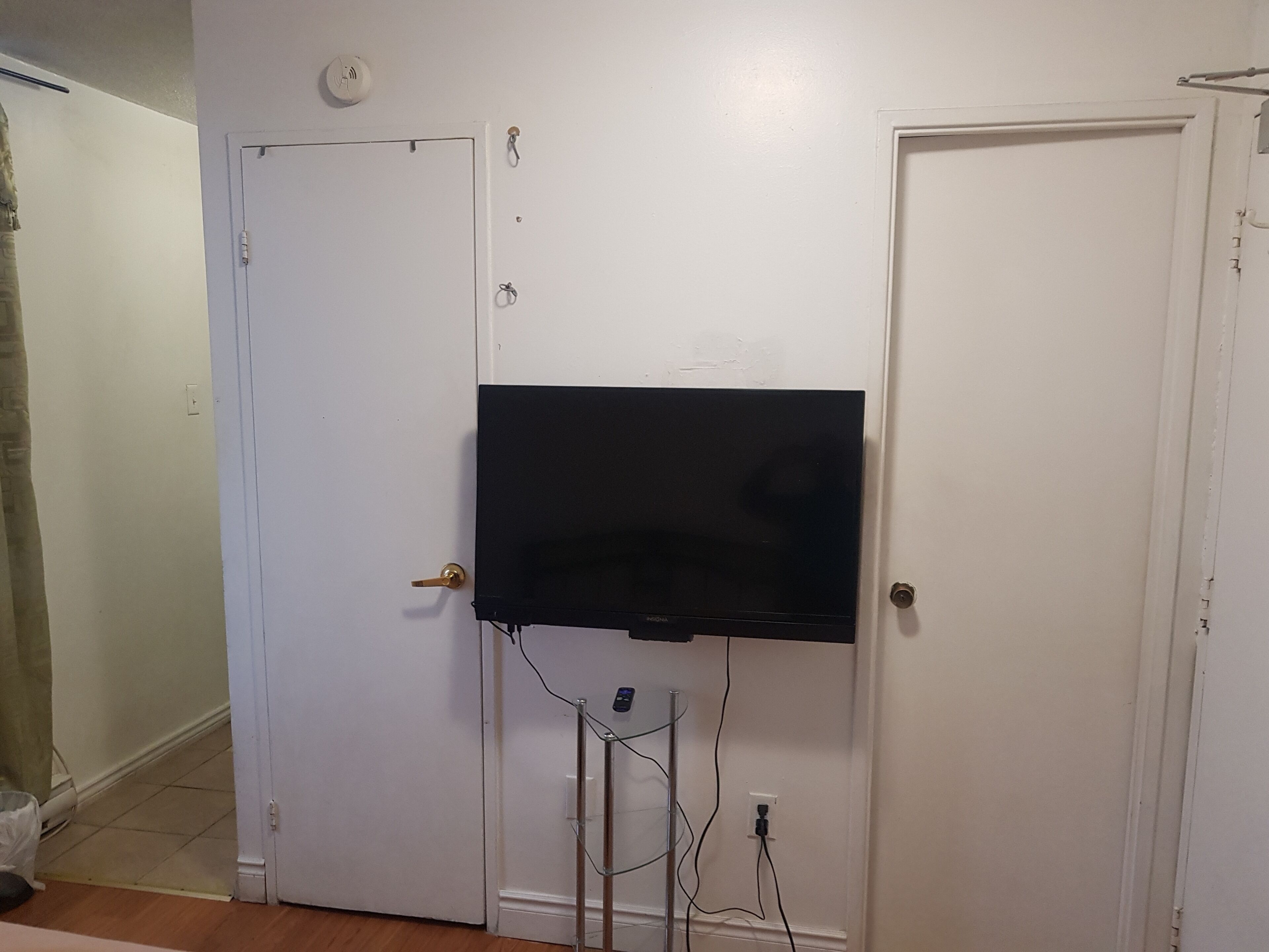 A room with a white door, a mounted flat-screen TV, and visible electrical outlets.