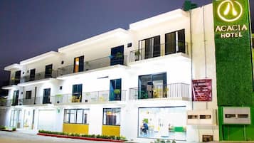 Un hotel de varios pisos con balcones, un toldo verde y un letrero que anuncia una oferta especial.