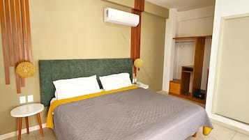 Un dormitorio moderno con cama, mesitas de noche, un equipo de aire acondicionado y una puerta que da a otra habitación.