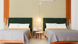 Una habitación de hotel con dos camas, una mesita redonda pequeña y una lámpara fijada a la pared.