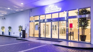The exterior of The Club at Brickell Bay, featuring a modern facade with glass doors and potted plants.