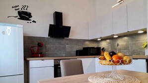Una cocina moderna con microondas, tostadora y una cesta de frutas sobre la encimera.
