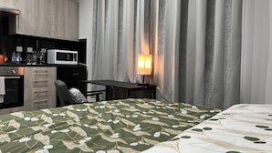 A hotel room with a bed, a desk, a microwave, and a minibar. - The Grand Bleu - Next to Tube station (London)