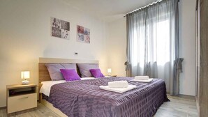 A neatly arranged bedroom with a large bed, two bedside tables, and a window with curtains. - Villa with pool, BBQ and games room (Valbandon)