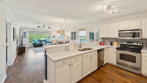 A modern kitchen with white cabinetry, stainless steel appliances, and a large island. - 3BR/2BA Pet-Friendly Condo with Pool on True Blue Golf Course (Pawleys Island)