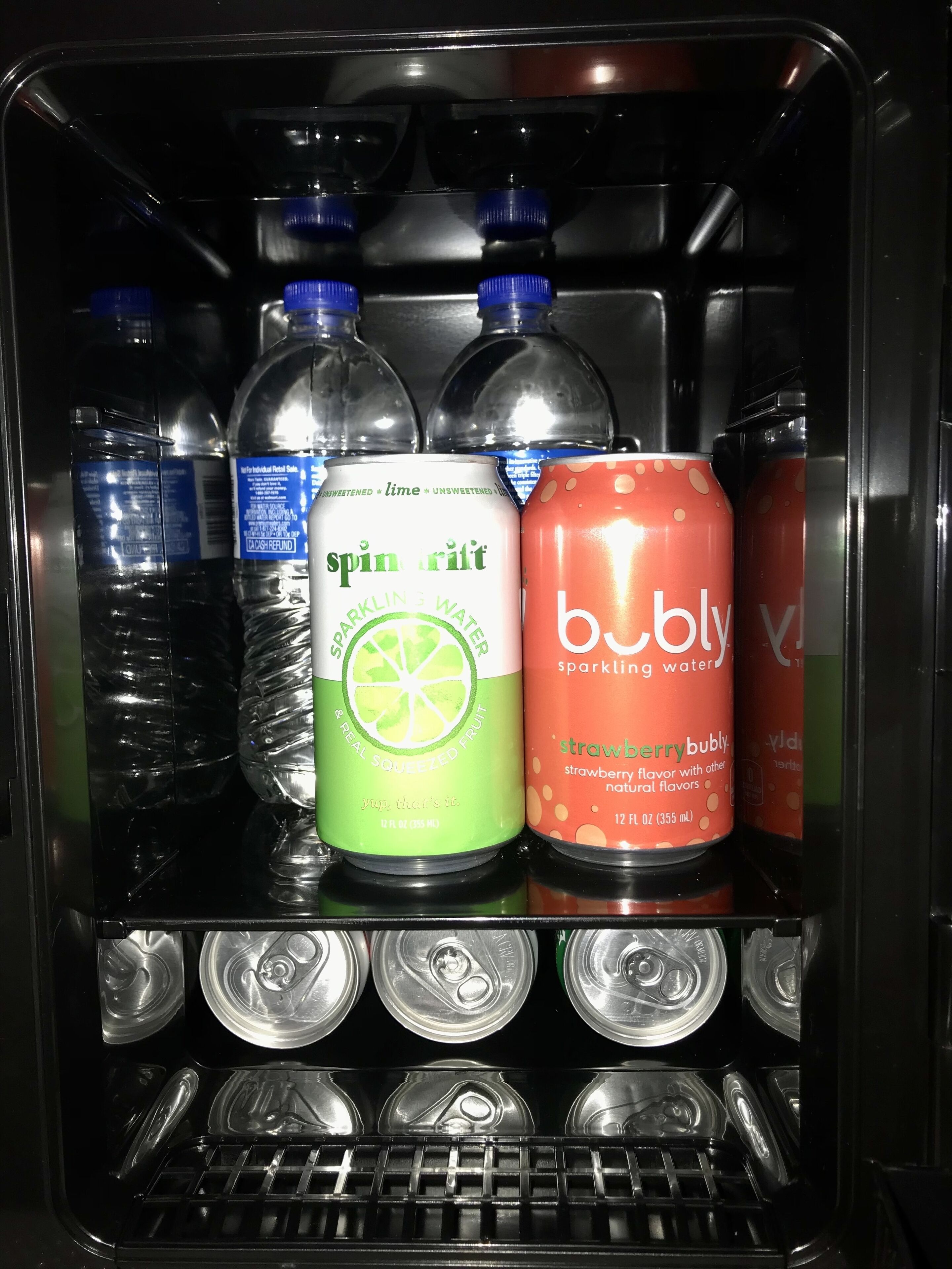 Een drankkoeler met verschillende drankjes, waaronder bruiswater, Spinrtit en Bublly.