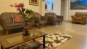 A living room with two sofas, a coffee table, and a decorative vase with flowers. - Inka House Inn (Machu Picchu)