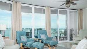 A spacious balcony with two blue reclining chairs and a beige sofa, offering a view of the cityscape. - Cozy Three Bedroom Bayside Unit. Complimentary Boat Slip. (Orange Beach)