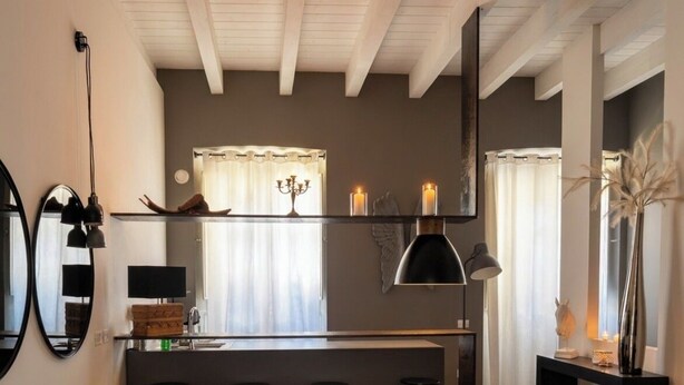 A modern living room with a sofa, ottoman, and a dining area with stools. - Luxury City Center Loft (Cagliari)