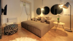 A modern living room with a sofa, ottoman, and round mirrors on the wall. - Luxury City Center Loft (Cagliari)