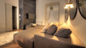 A bedroom with a large bed, a flat-screen TV, a marble wall, and a mirror. - Luxury City Center Loft (Cagliari)