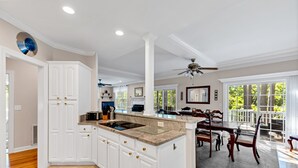A spacious kitchen with white cabinetry, a granite countertop, and a dining area with wooden chairs and a table.