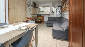 A compact living space with a dining area, a sofa, and a kitchen.