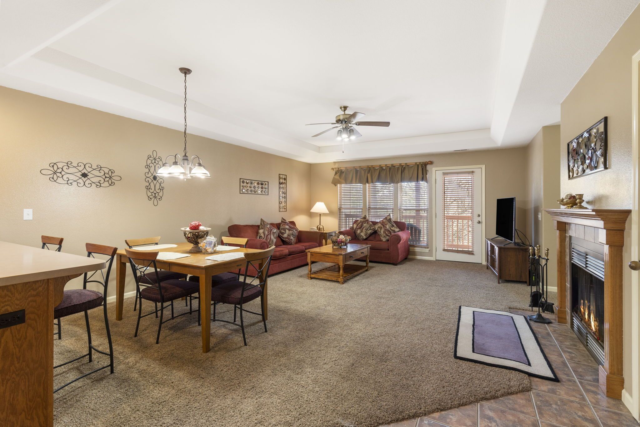 A living room with a dining area, a fireplace, and a ceiling fan.