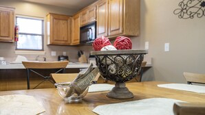 A kitchen with wooden cabinets, a microwave, and a decorative bowl with yarn balls.