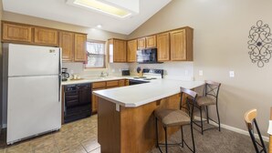 Una cocina con armarios de madera, un refrigerador blanco, un microondas y una isla grande con taburetes de bar.