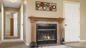 Una sala de estar con chimenea, un pasillo y una puerta.