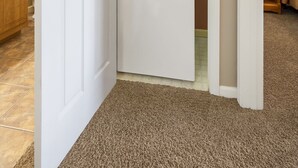 A laundry room with a stacked washer and dryer, a wooden cabinet, and a carpeted floor. - Cozy Suite with Kitchenette at Relaxing StoneBridge Village (Reeds Spring)