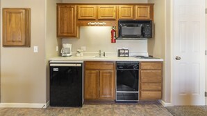 A compact kitchen with wooden cabinets, a microwave, a dishwasher, and a coffee maker. - Cozy Suite with Kitchenette at Relaxing StoneBridge Village (Reeds Spring)