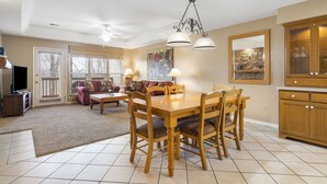 Un comedor con mesa y sillas de madera, una araña y una cocina con armarios de madera.