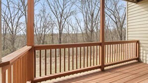 Eine Holzterrasse mit Geländer, die auf einen bewaldeten Bereich blickt.