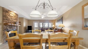 A dining area with a stone wall, a chandelier, and a television.