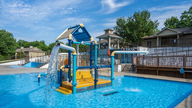 A water play area with a slide and climbing structure over a pool.