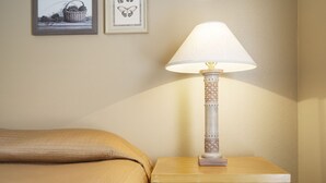 A neatly made bed with a beige blanket, a bedside table with a lamp, and two framed pictures on the wall. - Charming Suite with Kitchenette at StoneBridge Village (Reeds Spring)