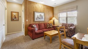 A cozy living room with a red sofa, wooden coffee table, and patterned armchair. - Charming Suite with Kitchenette at StoneBridge Village (Reeds Spring)