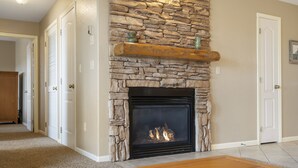 A stone fireplace with a mantel shelf, a wooden floor, and white doors. - Relaxing Condo with Fireplace, Jetted Tub, and Private Balcony (Reeds Spring)