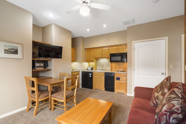 A compact living space with a dining area, a kitchenette, and a red couch.