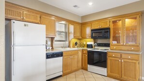 A kitchen with wooden cabinets, a white refrigerator, a microwave, a dishwasher, and a stove. - Charming Connecting Condo and Suite at StoneBridge Village Resort (Reeds Spring)