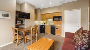 A compact living space with a dining area, a kitchenette, and a red couch. - Quaint Condo Suite in a Peaceful Community near Silver Dollar City (Reeds Spring)