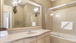 A modern bathroom with a large mirror, a sink, a glass shower enclosure, and a towel rack. - Quaint Condo Suite in a Peaceful Community near Silver Dollar City (Reeds Spring)