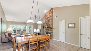 A dining area with a wooden table and chairs, a stone fireplace, and a stone wall. - Sweet Golf Condo in a Gated Community near Silver Dollar City (Reeds Spring)