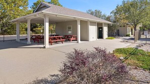 A covered picnic area with benches and a small building with a door. - Cute Queen Suite at StoneBridge  Village - minutes from SDC! (Reeds Spring)