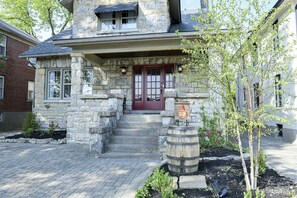 A stone house with a red door, a wooden barrel, and a small garden.