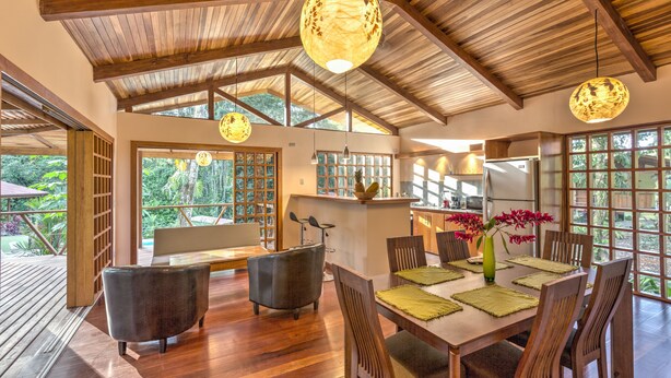 A spacious dining area with a wooden table, chairs, and hanging pendant lights. - Las Palomas Villas (Cahuita)