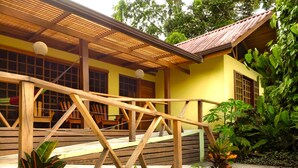 A wooden deck with a railing, surrounded by tropical plants. - Las Palomas Villas (Cahuita)
