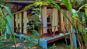 A rustic wooden structure with a covered porch, surrounded by lush greenery and tropical plants. - Las Palomas Villas (Cahuita)