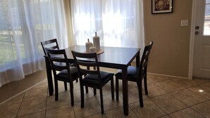 A dining area with a table, chairs, a chandelier, and sheer curtains. - Cattlemens Quarters beautiful ranch setting with fenced yards and a great deck! (Tyler)