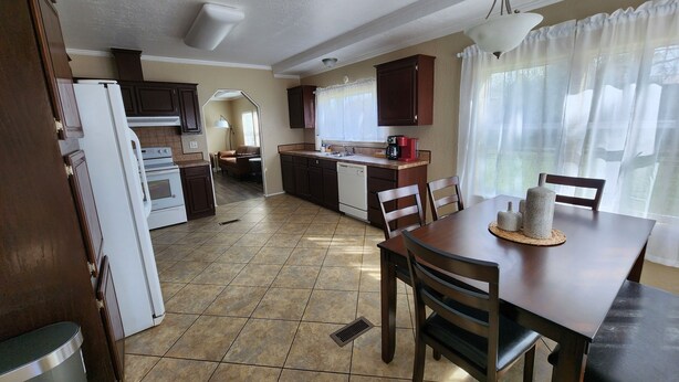 A kitchen with a dining area, a refrigerator, a stove, and a sink. - Cattlemens Quarters beautiful ranch setting with fenced yards and a great deck! (Tyler)