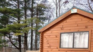 A wooden cabin with a green base, a window, and a deck. - 114) Pelican Log Cabin. Close to Hocking Hills State Park and more! (Logan)